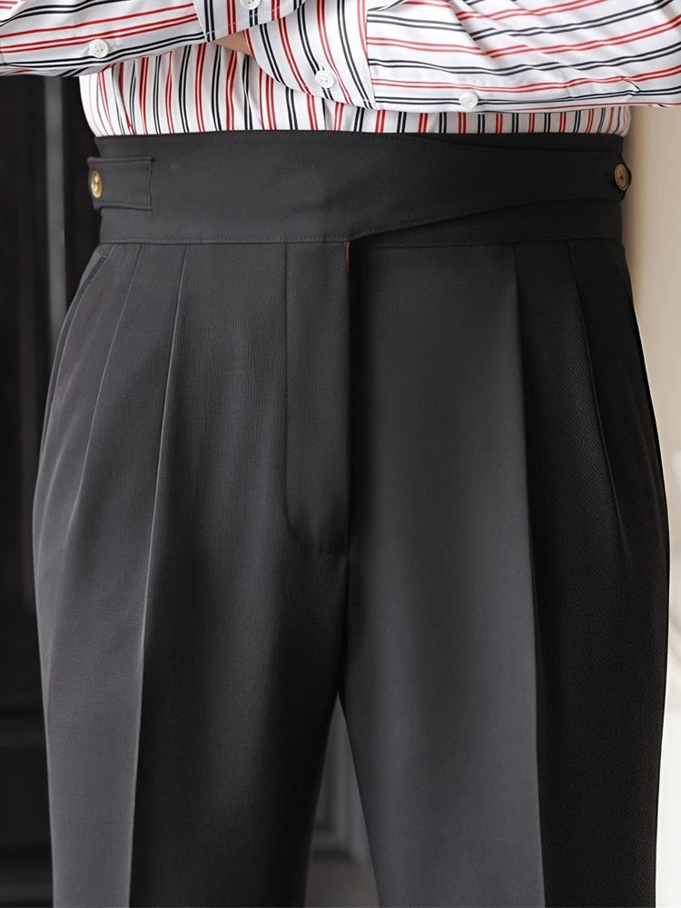 Person wearing a striped shirt and gray pleated pants with a blurred background