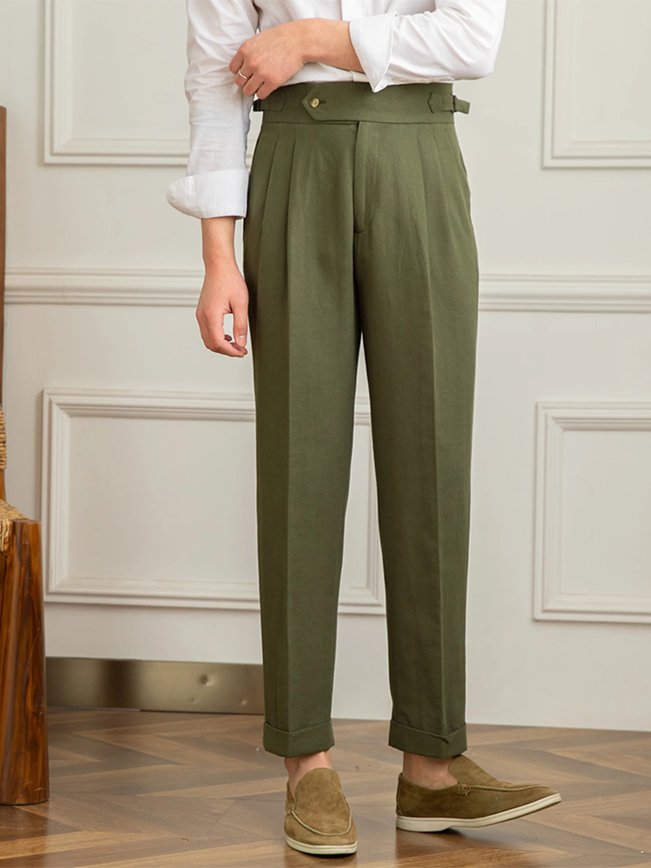 Person wearing green pants and a white shirt in a room with wooden flooring and white walls.